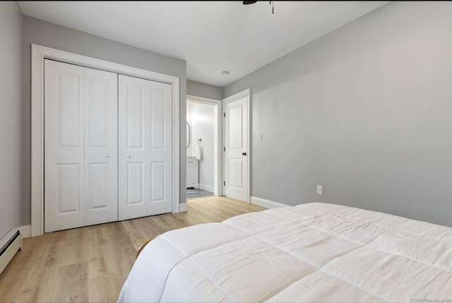 bedroom featuring light wood-type flooring, a baseboard radiator, and a closet