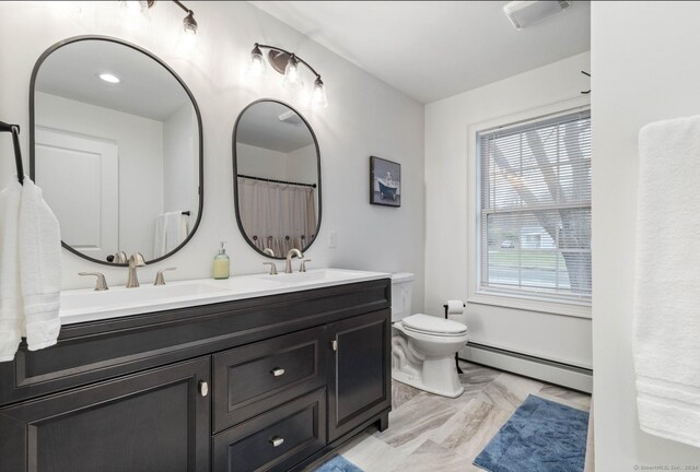 bathroom featuring toilet, vanity, and a baseboard heating unit