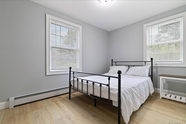 bedroom with light hardwood / wood-style floors and a baseboard radiator