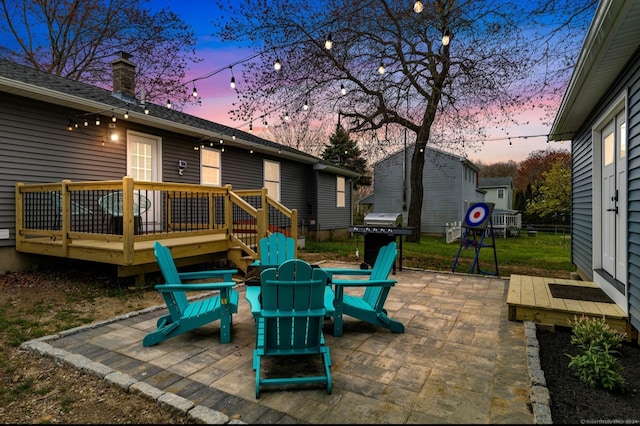 patio terrace at dusk featuring a grill and a wooden deck