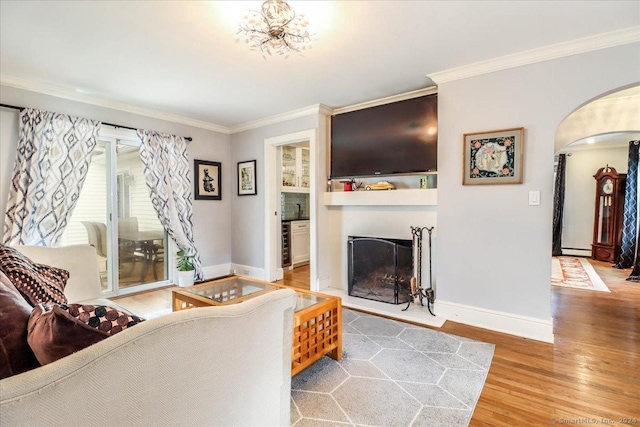 living room featuring hardwood / wood-style floors, a baseboard radiator, built in shelves, and crown molding