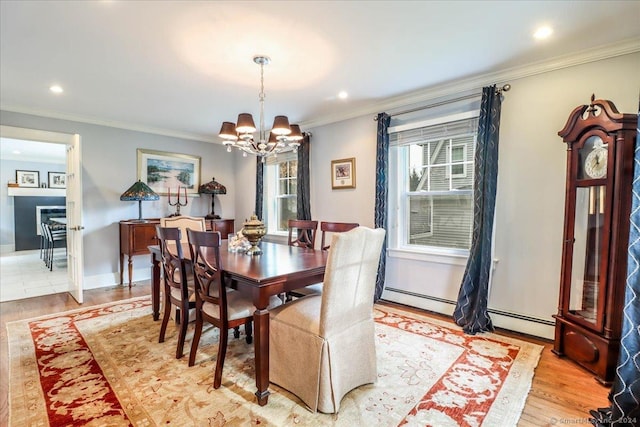 dining space featuring an inviting chandelier, ornamental molding, a baseboard heating unit, and light hardwood / wood-style flooring