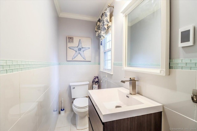 bathroom featuring tile patterned floors, crown molding, toilet, vanity, and tile walls