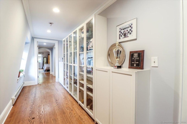 hall with light hardwood / wood-style floors, crown molding, and a baseboard radiator