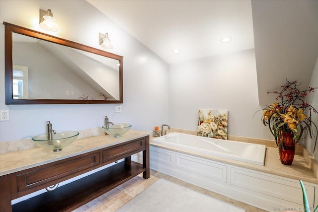 bathroom featuring tile patterned floors, vanity, lofted ceiling, and a bath