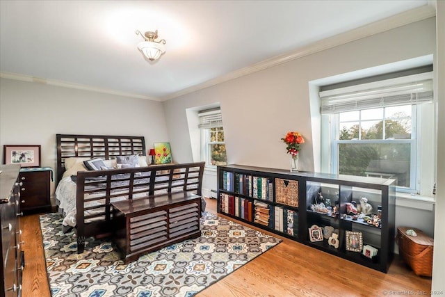 bedroom with multiple windows, crown molding, wood-type flooring, and a baseboard heating unit