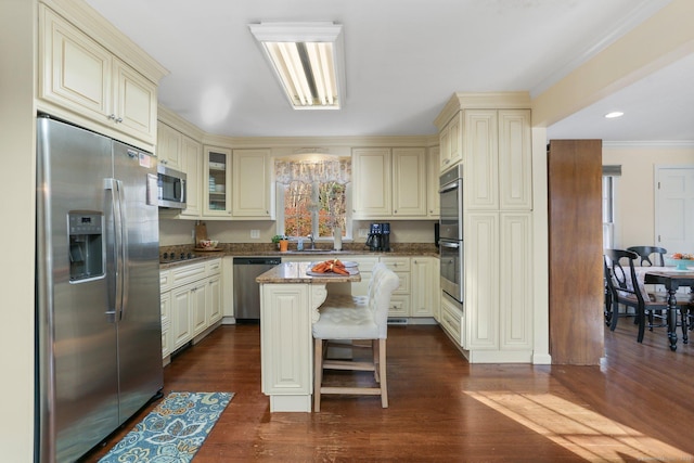 kitchen featuring dark hardwood / wood-style flooring, cream cabinets, a center island, and appliances with stainless steel finishes