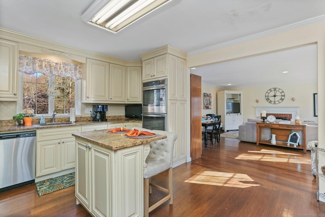 kitchen with sink, dark hardwood / wood-style floors, cream cabinetry, a kitchen island, and stainless steel appliances