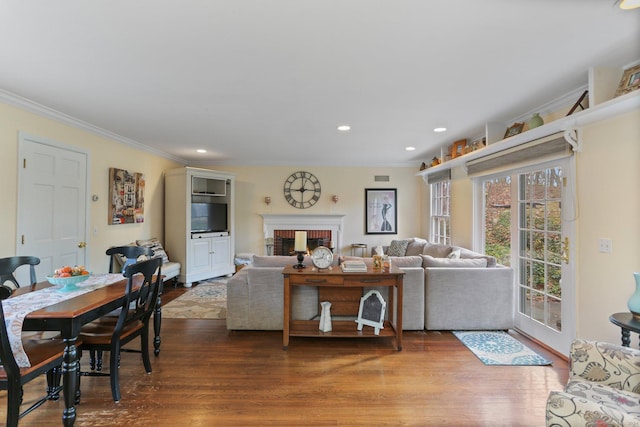 living room with dark hardwood / wood-style flooring, ornamental molding, and a brick fireplace