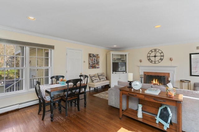 dining area featuring dark hardwood / wood-style floors, crown molding, baseboard heating, and a fireplace