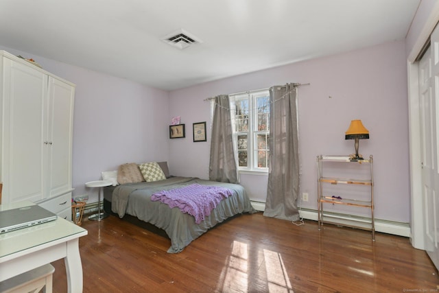 bedroom featuring a closet, dark wood-type flooring, and a baseboard heating unit