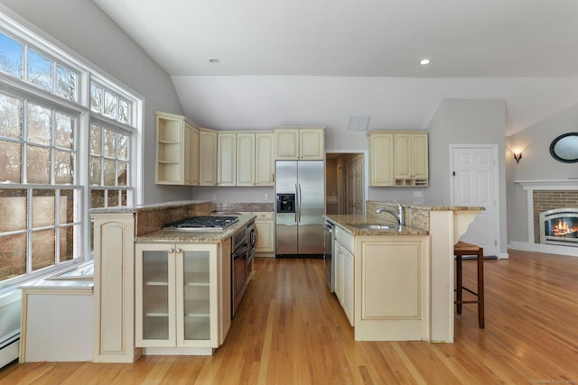 kitchen featuring a kitchen breakfast bar, stainless steel appliances, sink, light hardwood / wood-style floors, and lofted ceiling