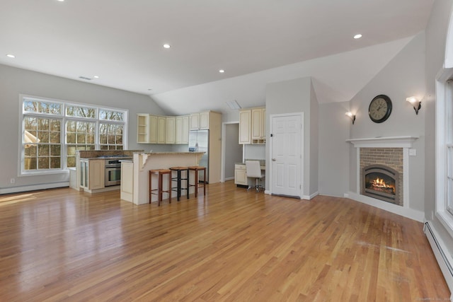 unfurnished living room with a fireplace, lofted ceiling, baseboard heating, and light hardwood / wood-style flooring