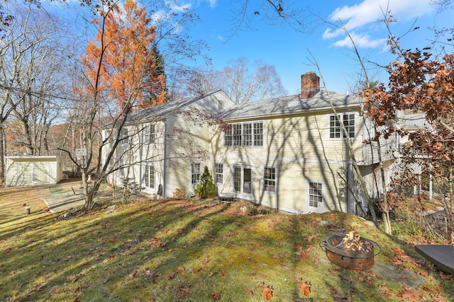 back of property featuring a fire pit and a lawn