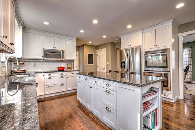 kitchen with white cabinetry, appliances with stainless steel finishes, a center island, and dark stone countertops