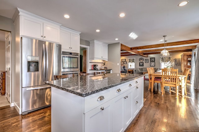 kitchen with pendant lighting, white cabinets, a center island, stainless steel appliances, and beamed ceiling