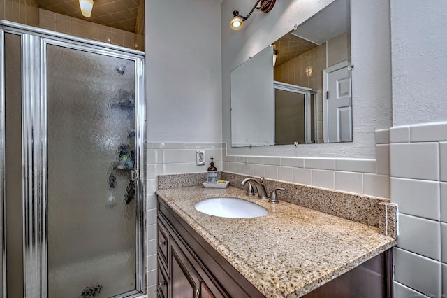 bathroom with vanity, tile walls, and a shower with door