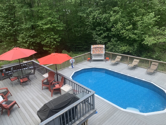 view of swimming pool featuring a wooden deck and area for grilling