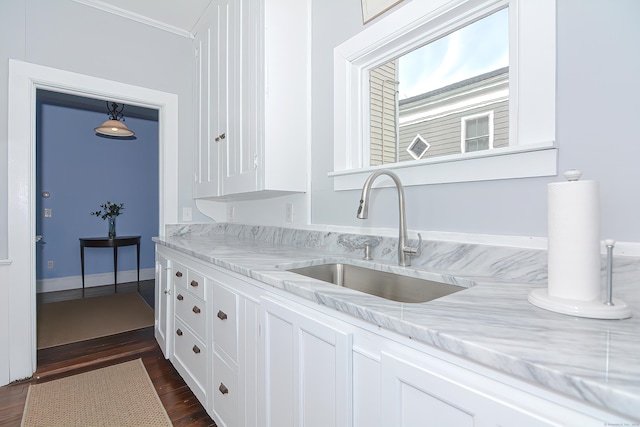 kitchen featuring light stone countertops, white cabinetry, sink, and dark wood-type flooring