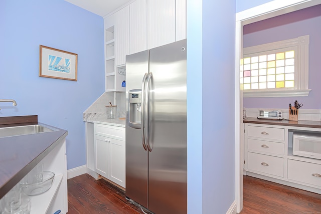 kitchen with white cabinetry, sink, dark wood-type flooring, stainless steel fridge, and decorative backsplash