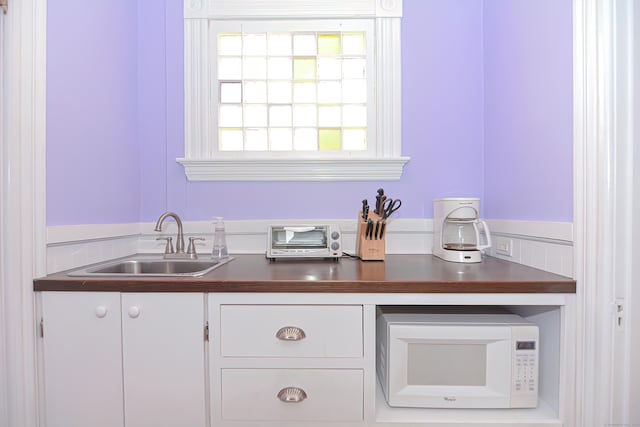 interior space with white cabinetry, sink, and wooden counters