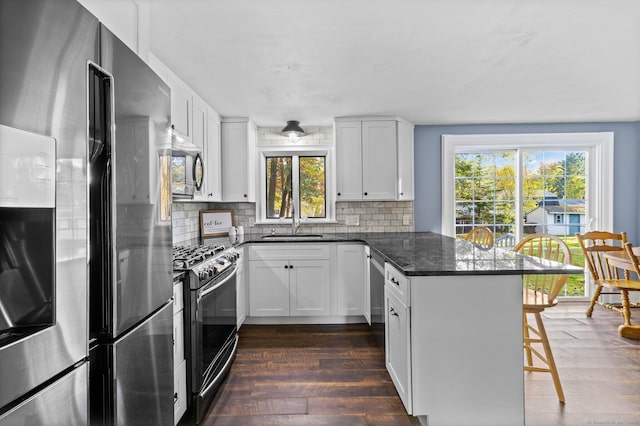 8 Fernwood Ave, Enfield, CT 06082 - kitchen featuring stainless steel appliances, a peninsula, a breakfast bar, backsplash, and healthy amount of natural light