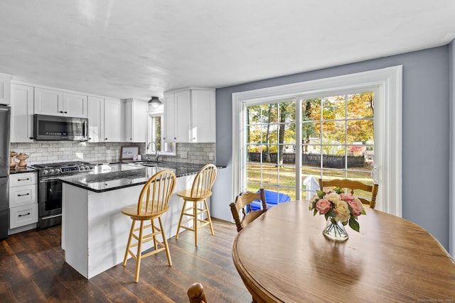 8 Fernwood Ave, Enfield, CT 06082 - kitchen with stainless steel appliances, backsplash, white cabinetry, a kitchen bar, and dark wood-type flooring