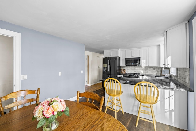 8 Fernwood Ave, Enfield, CT 06082 - kitchen featuring appliances with stainless steel finishes, a peninsula, backsplash, dark stone countertops, and white cabinetry
