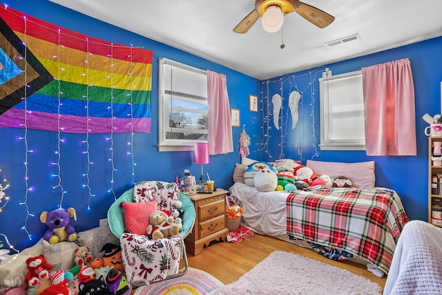 bedroom with multiple windows, ceiling fan, and hardwood / wood-style flooring