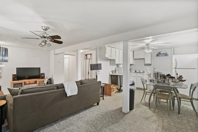 carpeted living room featuring ceiling fan and sink