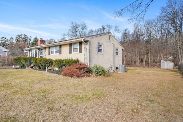 view of side of home featuring a yard, central AC, and a storage shed