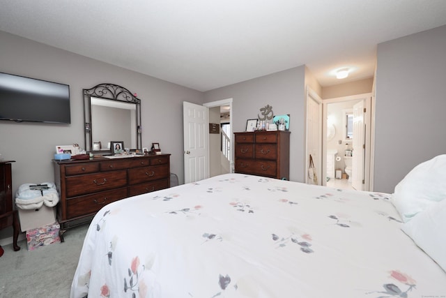 bedroom with ensuite bathroom and light carpet