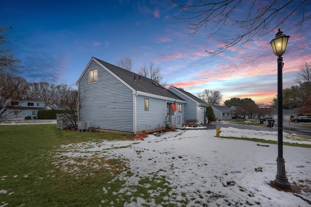 view of snowy exterior with cooling unit and a lawn