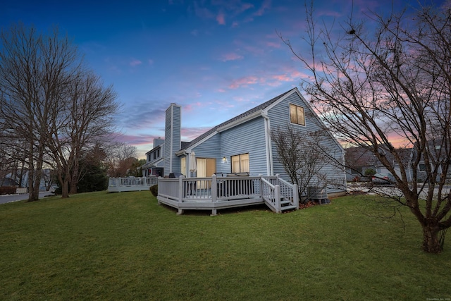 back house at dusk featuring a yard and a wooden deck