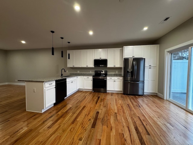 kitchen featuring white cabinets, light wood-type flooring, decorative light fixtures, and black appliances