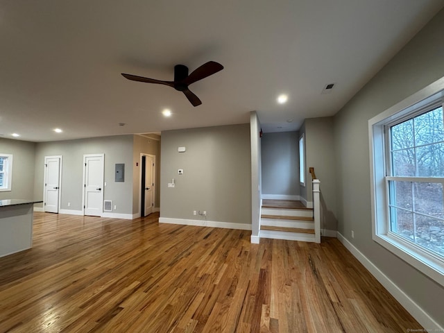 unfurnished living room featuring ceiling fan, electric panel, and light hardwood / wood-style flooring