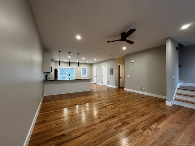 unfurnished living room featuring ceiling fan, wood-type flooring, and sink