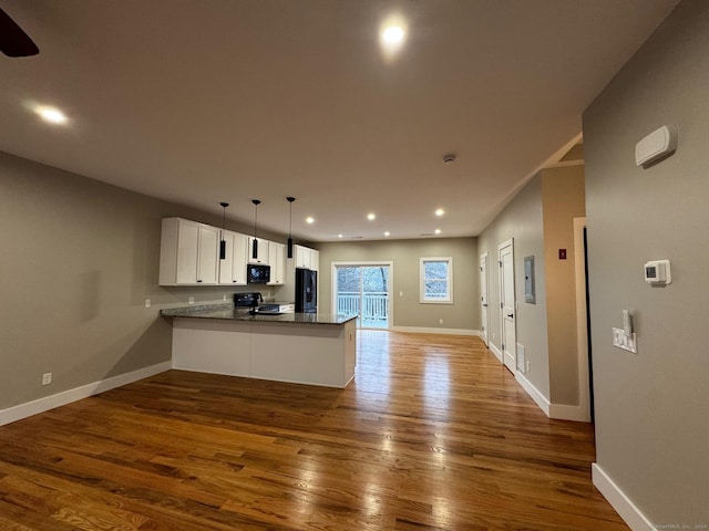 kitchen featuring black appliances, wood-type flooring, white cabinetry, and kitchen peninsula