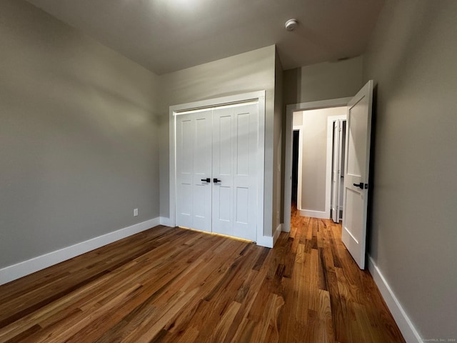 unfurnished bedroom with wood-type flooring and a closet