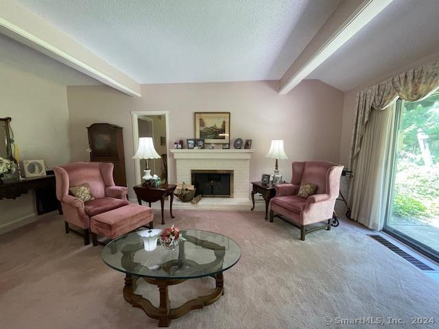 sitting room featuring a fireplace, beam ceiling, a textured ceiling, and light carpet