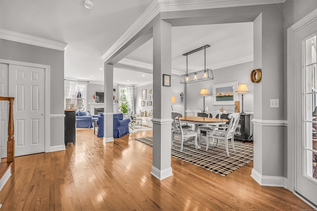 dining area with hardwood / wood-style flooring, ornamental molding, and decorative columns