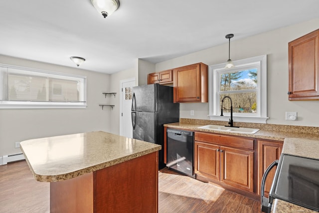 kitchen featuring sink, black appliances, pendant lighting, light hardwood / wood-style floors, and a kitchen island