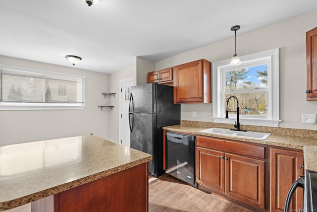 kitchen featuring hanging light fixtures, sink, black appliances, and light hardwood / wood-style flooring