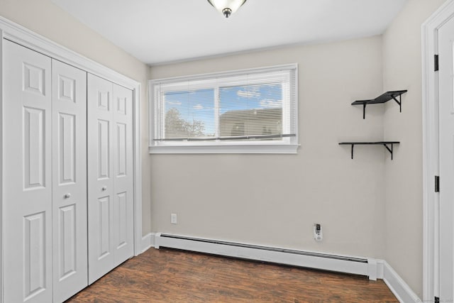 unfurnished bedroom with a closet, a baseboard radiator, and dark hardwood / wood-style floors