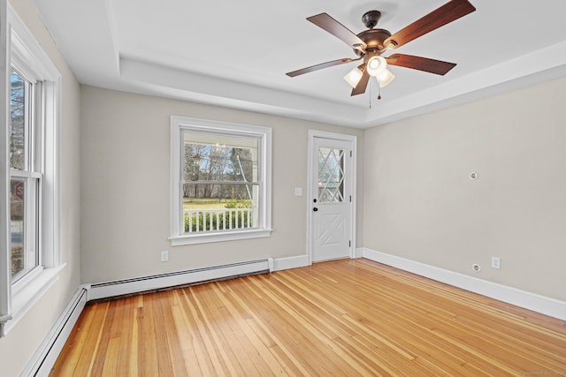 spare room with a tray ceiling, ceiling fan, hardwood / wood-style floors, and a baseboard heating unit