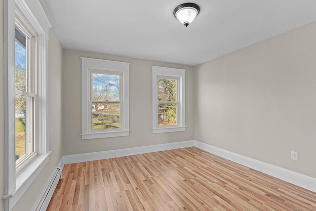 spare room featuring baseboard heating and light wood-type flooring