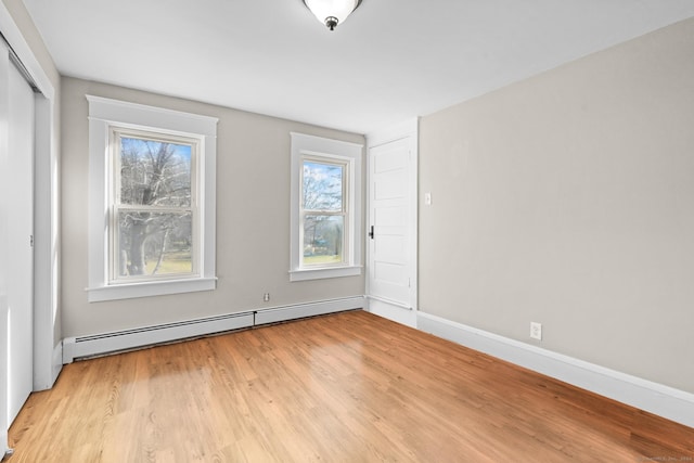 empty room featuring a baseboard radiator and light hardwood / wood-style floors