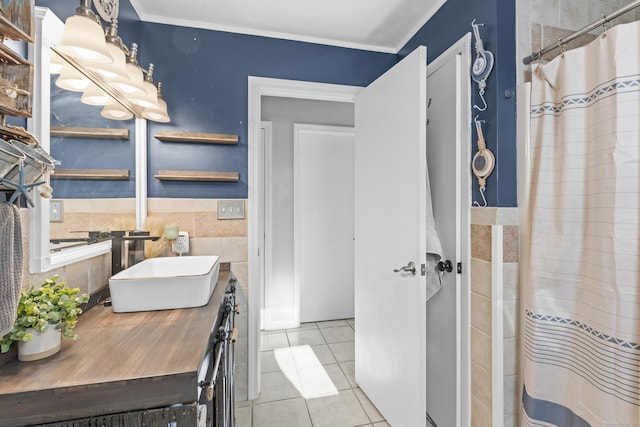 bathroom with tile patterned floors, tile walls, crown molding, and sink