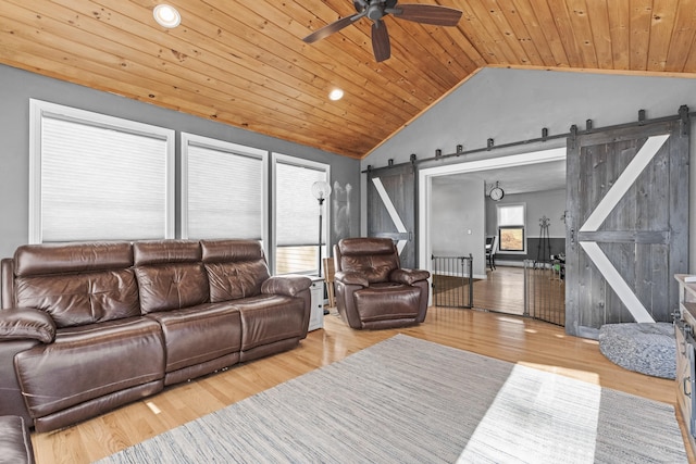 living room featuring lofted ceiling, a barn door, light wood-type flooring, and wooden ceiling