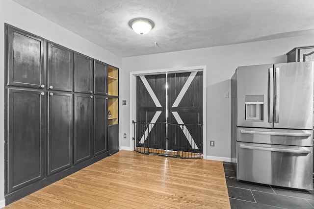 kitchen with stainless steel refrigerator with ice dispenser, a textured ceiling, and wood-type flooring